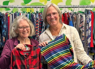 two women smiling and holding clothes